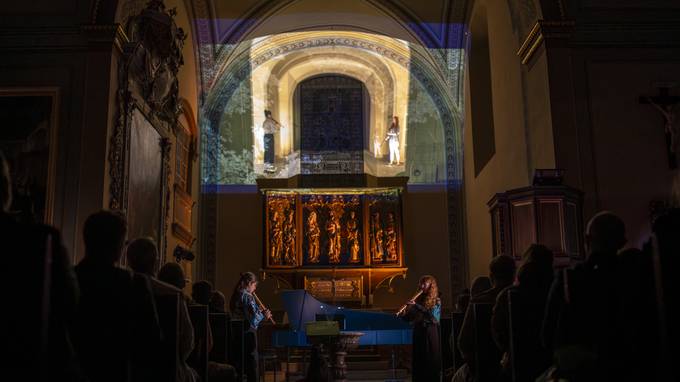 eine Kirche mit Projektion im Altarraum, eine Cembalistin und eine Flötistin  (öffnet Vergrößerung des Bildes)